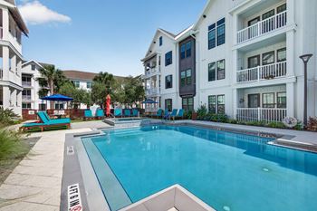 Custom pool area with fire pit lounge, grills, hot tub, and community tables